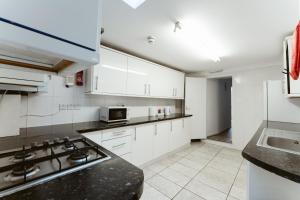 uma cozinha com armários brancos e um forno com placa de fogão em Plaistow Cosy Double Rooms - 8 em Londres