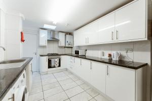 una cocina con armarios blancos y encimeras negras en Plaistow Cosy Double Rooms - 8 en Londres