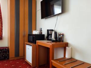 a room with a table with a microwave and a tv on the wall at Morena 203 in Klaipėda