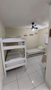 a room with two bunk beds and a ceiling fan at Kit Ocian in Praia Grande