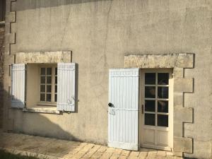 twee ramen en een deur aan de zijkant van een gebouw bij Maison au calme proche des cures in Jonzac