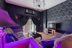 Sala de estar de color púrpura con sofá y TV en A Spooktacular Haunted Mansion. en Kissimmee