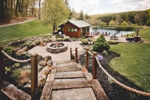 a garden with a log cabin next to a lake at Lake with Dock and Hot Tub Hocking Hills Cabin in Rockbridge