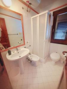 La salle de bains blanche est pourvue d'un lavabo et de toilettes. dans l'établissement Casa vacanze Magabù, à Cefalù