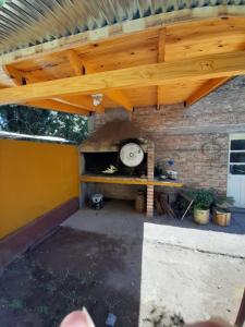 un patio con horno de pizza bajo un techo de madera en Complejo Los Platanos en General Alvear