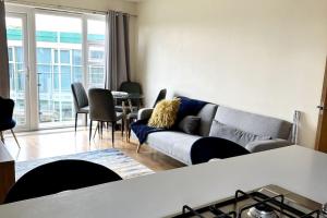 a living room with a couch and a table with chairs at Cosy 2 Bed Apartment 5 min walk from London Tube Station in Barkingside