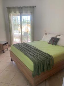 a bed with a green blanket on it in a bedroom at Beralmar Asilah Chez FATIMA in Asilah