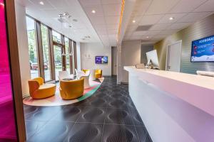 a waiting area in a hospital with yellow chairs and tables at prizeotel Antwerp-City in Antwerp