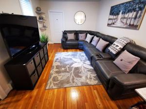 Location+Comfort+Convenience في بوسطن: غرفة معيشة مع أريكة جلدية وتلفزيون بشاشة مسطحة