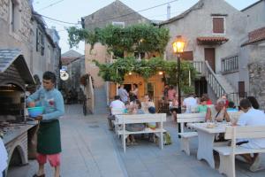 a group of people sitting at tables in an alley at Holiday Home Mirta in Pakoštane