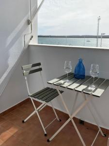uma mesa com dois copos e uma cadeira na varanda em Apartamento Atardeceres em Ayamonte