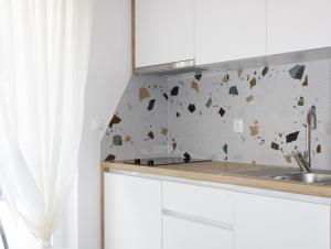 a kitchen with white cabinets and a sink at Apartments Maris in Baška Voda +206 photos