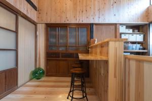 eine Küche mit Holzwänden und eine Bar mit einem Stuhl in der Unterkunft guesthouse碧 in Okinoshima