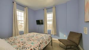 a bedroom with a bed and a chair and two windows at Atlantic Suite by the Boardwalk 2D in Atlantic City