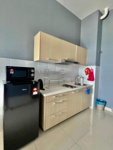 a kitchen with a black refrigerator and a microwave at Modern Dpulze Soho fit 4pax,Netflix provided in Cyberjaya
