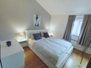 a white bed with blue pillows in a bedroom at Apartment Anita in Umag