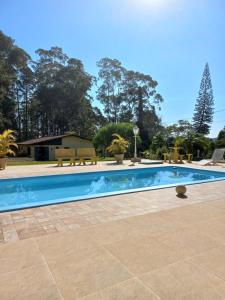 a swimming pool in a yard with benches around it at Sítio Toa Toa in São Roque