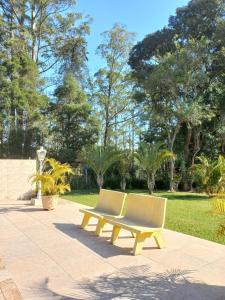 a yellow bench sitting on a sidewalk in a park at Sítio Toa Toa in São Roque