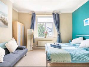 a blue bedroom with a bed and a couch at The Mews - less than 1km to City Centre - Stadium - Castle - 10 min walk in Cardiff