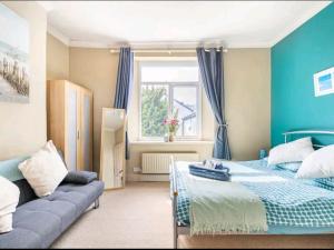 um quarto azul com uma cama e um sofá em The Mews em Cardiff