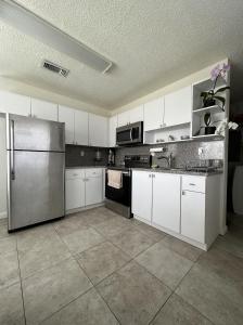 a kitchen with white cabinets and a stainless steel refrigerator at Miami's Cozy Tropical Getaway in Miami