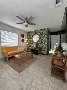 Miami's Cozy Tropical Getaway في ميامي: غرفة معيشة مع أريكة ومروحة سقف