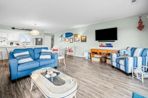 a living room with blue couches and a tv at Colony by the Sea #201 in Indian Beach