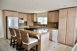a kitchen with wooden cabinets and a island with bar stools at Beach House located in quiet community. in Oxnard