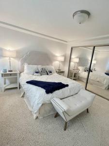 a white bedroom with a large bed and a mirror at Beach House located in quiet community. in Oxnard