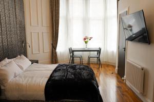 um quarto com uma cama e uma mesa com uma televisão em S.H Apartments em Glasgow