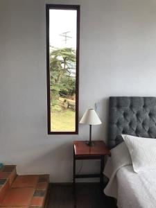 1 dormitorio con 1 cama y 1 mesa con lámpara en Despierte con la naturaleza, en Cogua