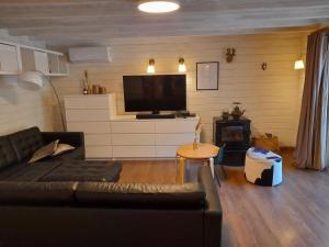 ein Wohnzimmer mit einem Sofa und einem Flachbild-TV in der Unterkunft Cozy chalet in a nature reserve with garden in Oud-Turnhout