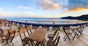 una terraza con sillas y mesas en la playa en 自家源泉の宿 竜宮の使い Ryugu no Tsukai, en Higashiizu