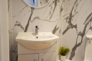 uma casa de banho com um lavatório branco e um espelho. em S.H Apartments em Glasgow