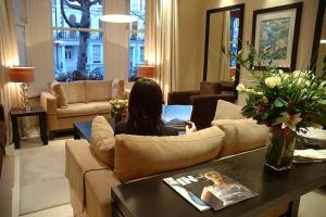 a woman sitting on a couch in a living room with a laptop at The Beaufort in London