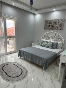 a white bedroom with a bed and a window at Maison tnazefti in Djerba