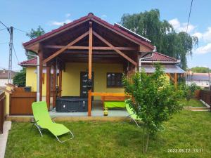 uma pequena casa amarela com cadeiras verdes no quintal em Holiday home in Kisnana - Ostungarn 44896 em Kisnána