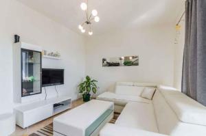 a white living room with a white couch and a tv at Apartment in Dramalj 44160 in Dramalj