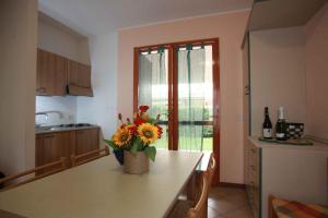 ロゾリーナ・マーレにあるApartment in Rosolina Mare 44965の花瓶に花が飾られたテーブルのあるキッチン