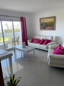 a living room with two white couches and pink pillows at Apartamento frente al Mar in La Francia