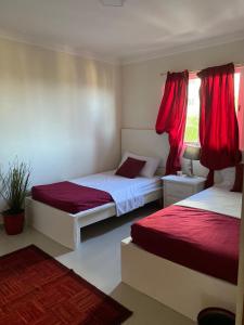 two beds in a bedroom with red curtains at Apartamento frente al Mar in La Francia