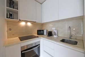 cocina con armarios blancos, fregadero y microondas en FLH Boavista Flat III en Oporto