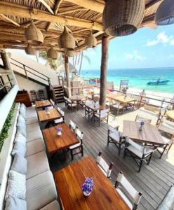 an outdoor patio with tables and chairs and the ocean at Casa Tucan. A contemporary holiday or work nest in Puerto Morelos