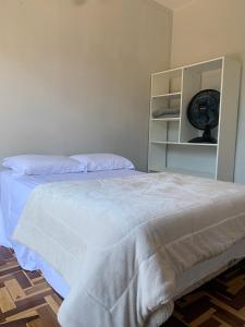a bedroom with a white bed with a fan at Pousada Hostel Dodora in Bento Gonçalves