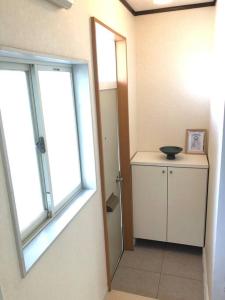 Zimmer mit 2 Fenstern, einem kleinen Schrank und einem Spiegel in der Unterkunft Chichibu Mizuno-stay 水野ステイ最大６名様 in Chichibu