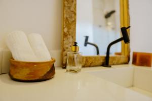 umywalkę w łazience z dozownikiem mydła i lustrem w obiekcie Vila Caiada Guest House w mieście Luis Correia