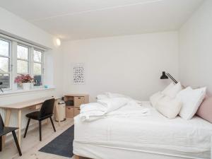 a white bedroom with a desk and a bed with white pillows at 5 person holiday home in Tisvildeleje in Tisvildeleje