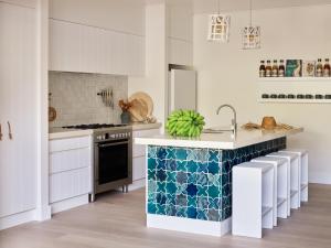 a kitchen with white cabinets and blue and white tiles at Atlantic Byron Bay in Byron Bay