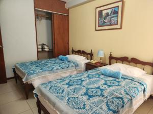 Habitación de hotel con 2 camas con sábanas azules y blancas en Hotel Las Lineas en Nazca