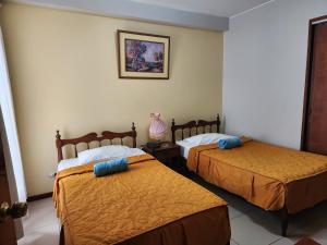 2 camas en una habitación de hotel con sábanas de color naranja en Hotel Las Lineas en Nazca